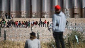 Migrants line up at the US border wall 