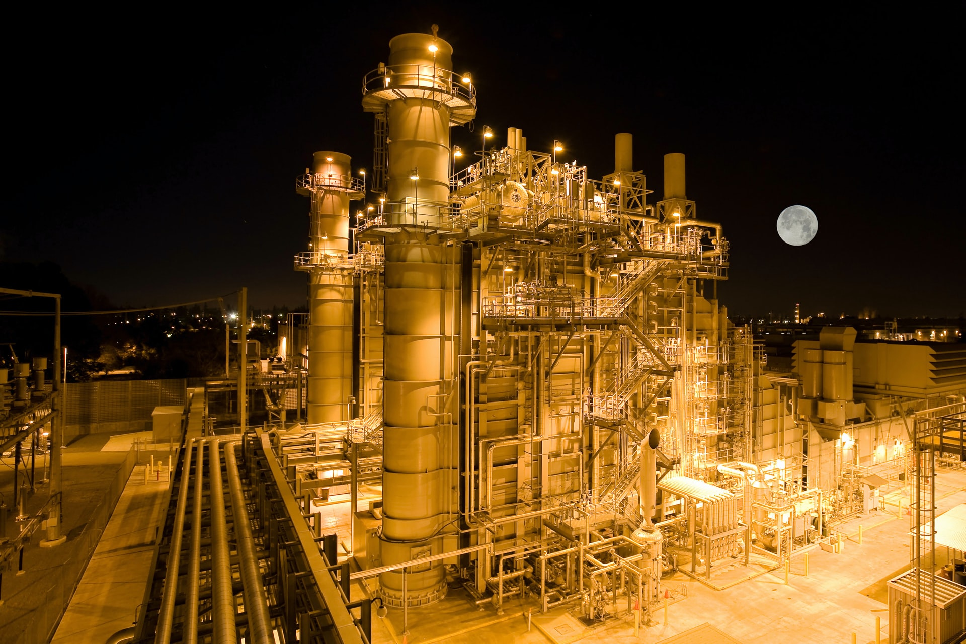 An aerial view of a power plant at night, with the moon in the background