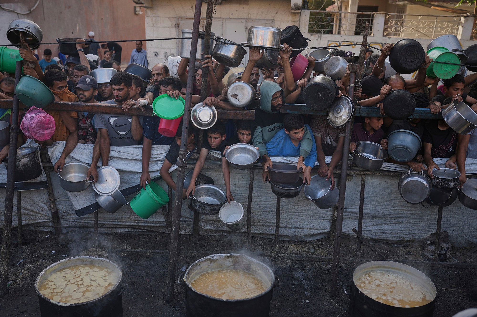 Palestinians struggle to get donated food at a community kitchen in Gaza City, northern Gaza Strip, Monday, July 14, 2025. 