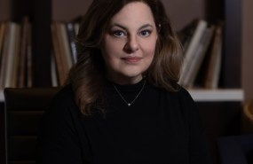 Rose Barbuto is pictured from the shoulders up wearing a black sweater, smiling softly into the camera.
