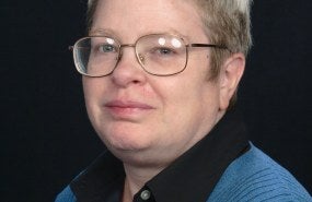 Stephanie Mercier is pictured from the shoulders-up wearing a blue sweater over a black button-down.
