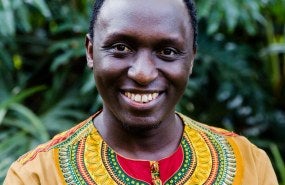 Cedric is pictured form the shoulders up in a yellow shirt, smiling into the camera.
