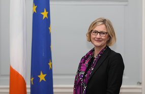 Sonja Hyland smiling in front of the Irish and European Union flags.