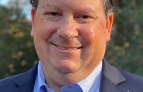 Eric Miller Headshot; Man in light blue shirt and black jacket