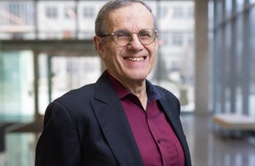 Headshot of Robert Rosner wearing dark red shirt, black jacket, and smiling