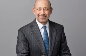 Blankfein headshot wearing dark grey jacket, blue tie, in front of light grey background