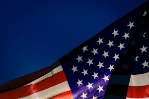 American flag, waving in front of a dark blue sky