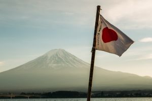 Japan flag waving near a body of water with a mountain in the background