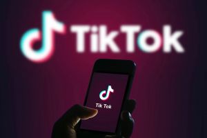 An image of a wall and phone with "TikTok" written on them. 