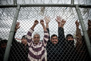 Immigrants stand behind a fence at a detention centre in the Amygdaleza suburb of western Athens