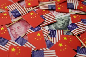 A US dollar banknote featuring American founding father Benjamin Franklin and a China's yuan banknote featuring late Chinese chairman Mao Zedong are seen among US and Chinese flags.