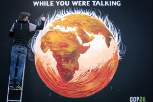 An artist finishes a mural of the earth on fire with the caption "while you were talking."