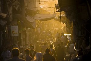 A street market in Syria with pedestrians and a hazy sunset