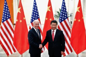 President Biden and Xi Jinping shaking hands in front of flags in 2013.