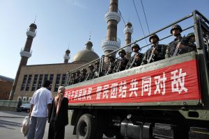An ethnic Uighur couple waits as a truck loaded with Chinese paramilitary police goes by in China's Xinjiang Autonomous Region 