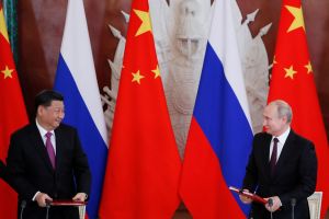 Presidents Xi and Putin look at each other while standing at separate podiums