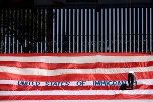 A man writes on a large U.S. flag as part of a protest called 'United States of Immigrants'