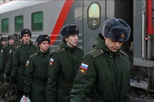 Russian conscripts called up for military service walk along a platform before boarding a train