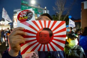 : Holding a mock rising sun flag of Japan disgraced with a portrait of South Korean President Yoon Suk-Yeol, a man attends protest marches in front of the Japanese Embassy in Korea