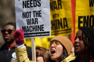 a protester holds a sign that says "not the war machine"