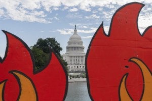 the U.S. Capitol is seen between cardboard cutouts of flames during a climate change protest