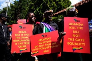 Activists hold red placards with yellow writing during their picket against Uganda's anti-homosexuality bill