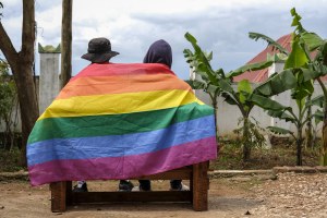 A gay Ugandan couple cover themselves with a pride flag as they pose for a photograph in Uganda