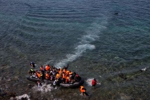Migrants and refugees arrive by dinghy after crossing from Turkey to the island of Lesbos, Greece.