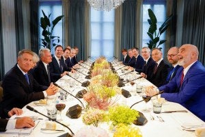 NATO leaders attend working dinner, viewed at the end of a table with white tablecloth and yellow centerpieces.