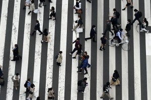 People walk along a pedestrian crossing in Japan.