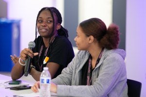 Young woman talking into a microphone.