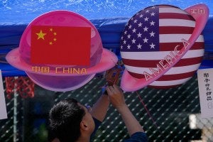 A vendor sets up foods and beverages at a booth displaying planets shaped of China and American flags