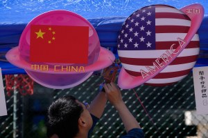 A vendor sets up foods and beverages at a booth displaying planets shaped of China and American flags