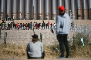 Migrants line up at the US border wall 