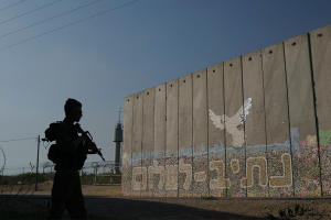 A member of the Israeli forces stands next to a wall with Hebrew writing reading "Path to Peace" at the Kibbutz Netiv Haasara near the border with Gaza Strip, Israel on November 17, 2023.