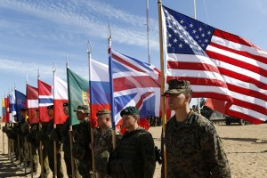 Soldiers from NATO countries hold their respective flags