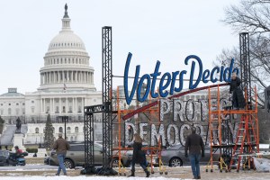  With the US Capitol in the background, people walk past a sign that says Voters Decide Protect Democracy