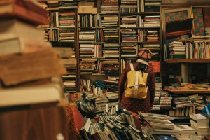 A person wearing a backpack browses shelves at a bookstore.