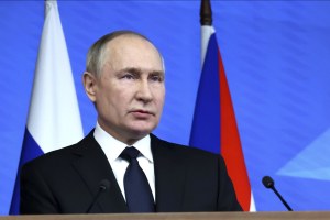 Russian President Vladimir Putin speaks in front of a Russian flag