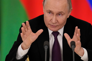 Russian President Vladimir Putin holds his hands up and speaks into a microphone during a news conference on March 13, 2025.