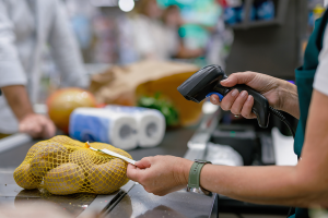 A grocery store cashier scans a bag of potatoes at the checkout counter.