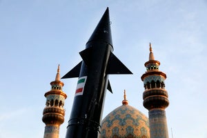 A model of a missile is carried by Iranian demonstrators as minarets and dome of a mosque is seen at background 