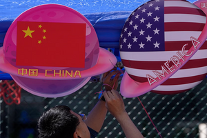 A vendor sets up foods and beverages at a booth displaying planets shaped of China and American flags