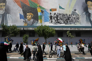Iranian worshippers walk past a mural showing the late revolutionary founder Ayatollah Khomeini, right, Supreme Leader Ayatollah Ali Khamenei, left, and Basij paramilitary force in Tehran, Iran on April 19, 2024.