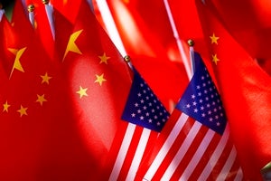 Two miniature American flags rest in front of a larger group of Chinese flags.