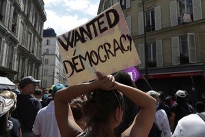 A protestor holds up a sign reading "WANTED DEMOCRACY" at a protest in France on July 31, 2021.