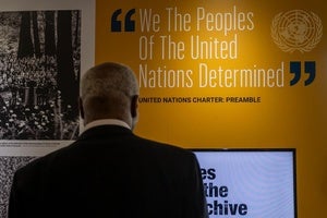 A man looks at a quote from the United Nations Charter: Preamble on a wall that reads: "We The Peoples Of The United Nations Determined."