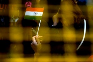 A woman waves a handheld Indian flag.