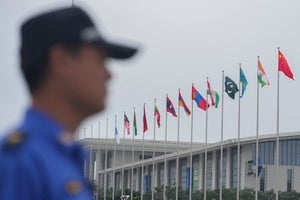 A security guard stands near the flags of Shanghai Cooperation Organization member states outside the venue in Tianjin, China on August 30, 2025.