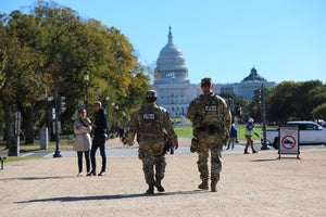 National Guard soldiers walking in front of capital building, adjacent to civilians